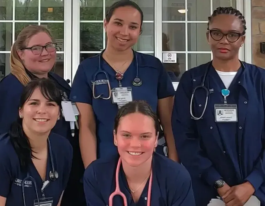 Group of Herzing nursing students in blue scrubs smiling for photo